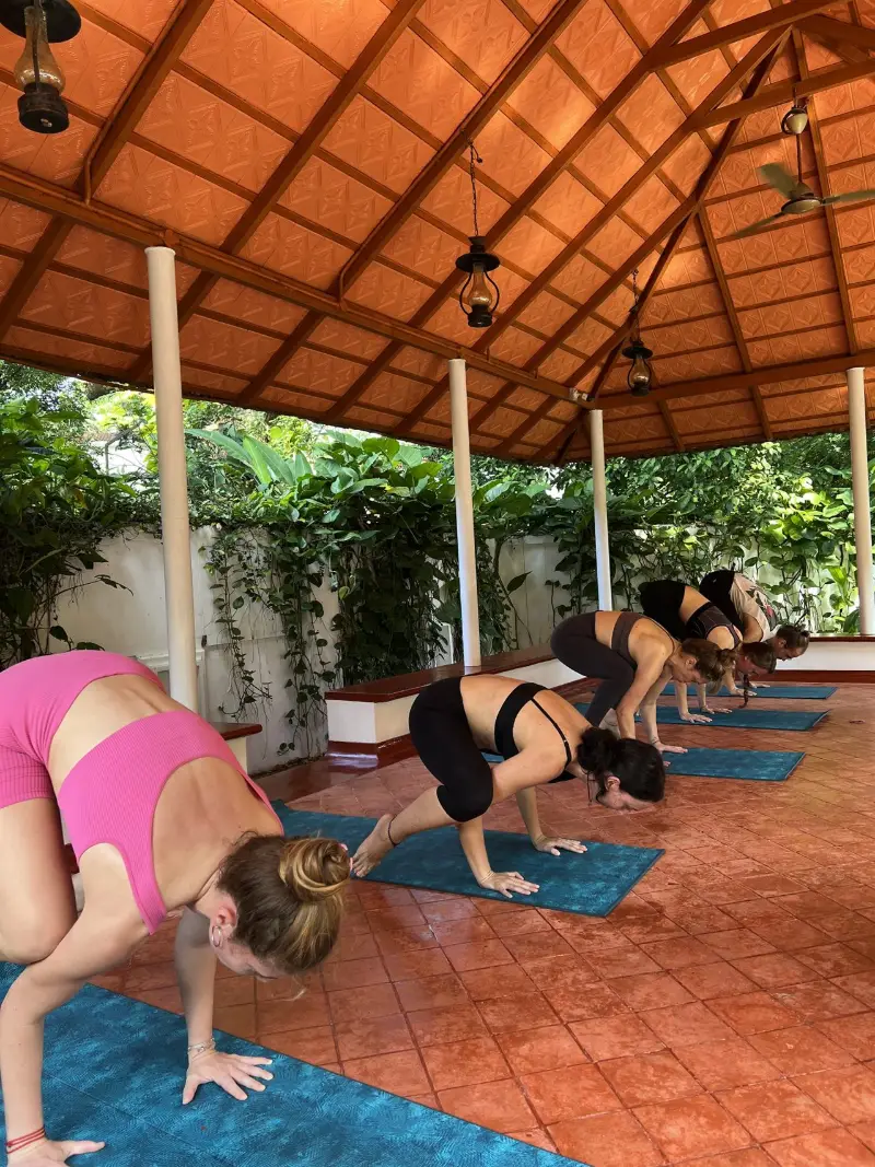 Students practising arm balances in the open-air pavilion